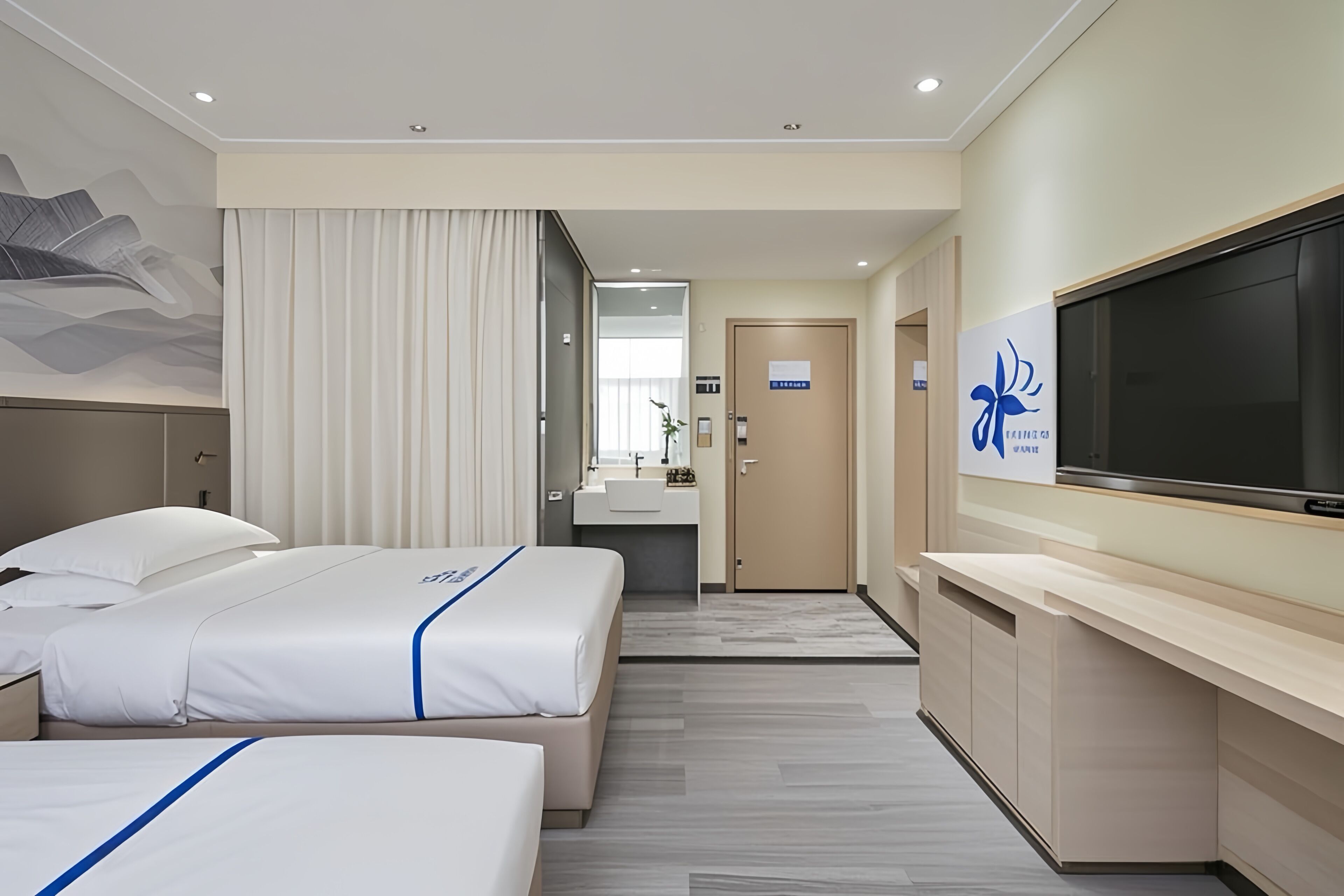 Ein Hotelzimmer mit zwei Betten, einem Fernseher, einem Schreibtisch und einem durch eine offene Tür erreichbaren Badezimmer.
