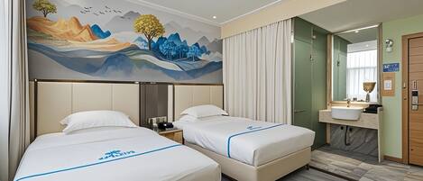 Une chambre d’hôtel avec deux lits, une fresque murale, une salle de bain avec un lavabo et un miroir, et une porte en bois.