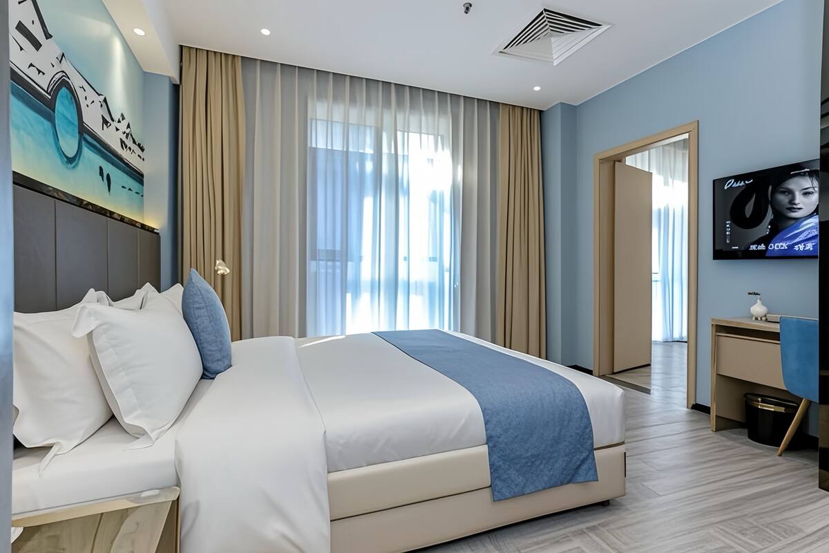 Ein modernes Hotelzimmer mit einem großen Bett, einem Flachbildfernseher und einem Bild an der Wand.