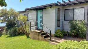 Ein modernes Haus mit einer grünen Tür, einer Treppe, die zum Eingang führt, und einem gepflegten Garten.