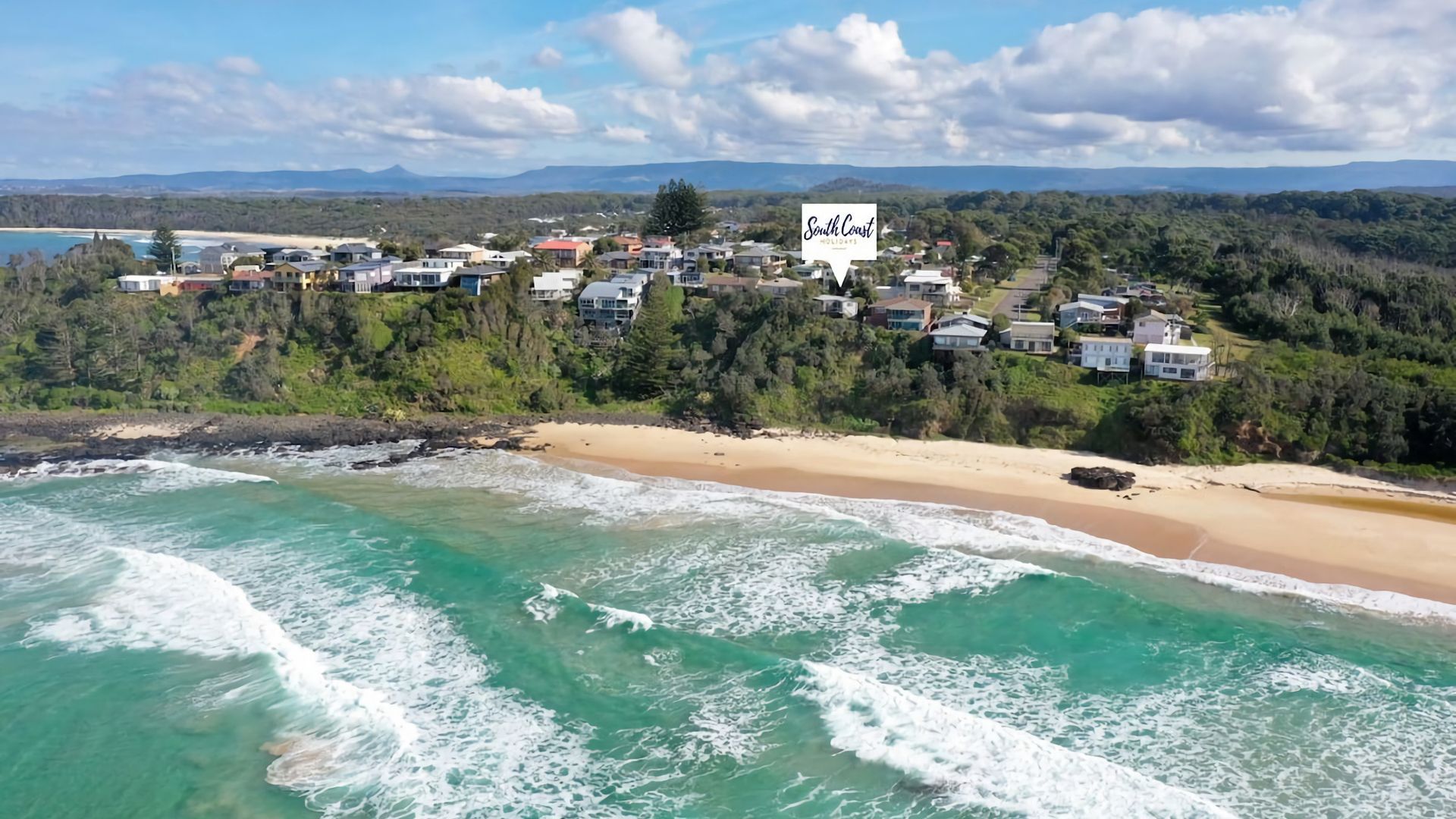 A coastal residential area with houses overlooking a beach and ocean.