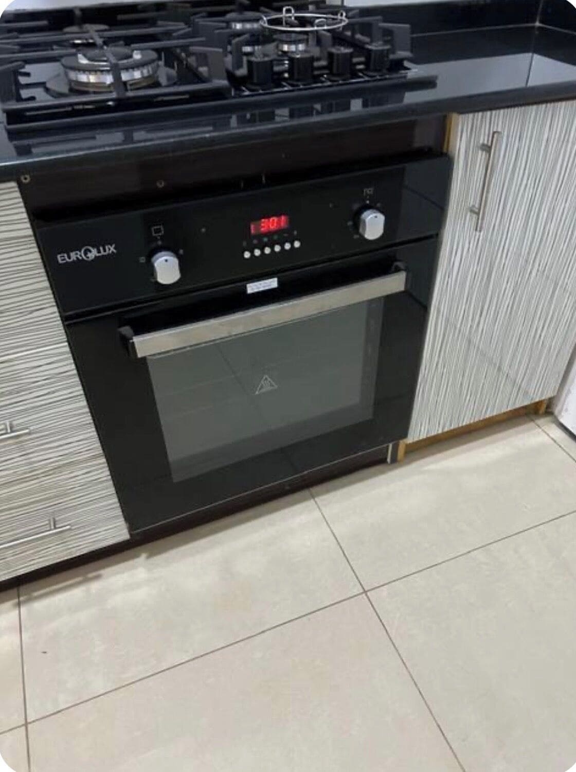 Une cuisine équipée d’une cuisinière et d’un four intégrés, dotés d’un écran numérique et de boutons de commande.