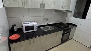 Une cuisine moderne avec des meubles blancs, un plan de travail noir, un four à micro-ondes, un évier et une cuisinière.