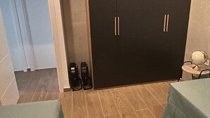 Una camera d'albergo con un letto, un tavolino con una lampada e un armadio a due ante.
