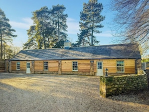 Un bâtiment de style rustique, avec une allée en gravier, un revêtement en bois et un mur en pierre.
