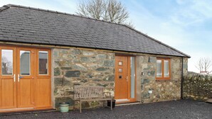A stone building with a sloped roof, wooden doors, and windows. - 1 bedroom accommodation in Tregarth, near Bangor (Tregarth, near Bangor)