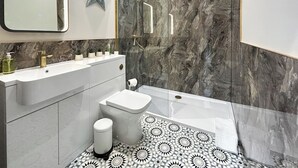 A modern bathroom with a vanity, a toilet, a shower, and patterned floor tiles. - 1 bedroom accommodation in East Stoke, near Newark (East Stoke, near Newark)