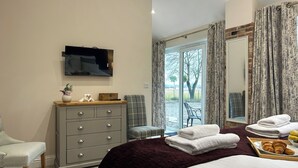 A hotel room with a bed, a dresser, a television, a chair, and a view of the outdoors. - 1 bedroom accommodation in East Stoke, near Newark (East Stoke, near Newark)