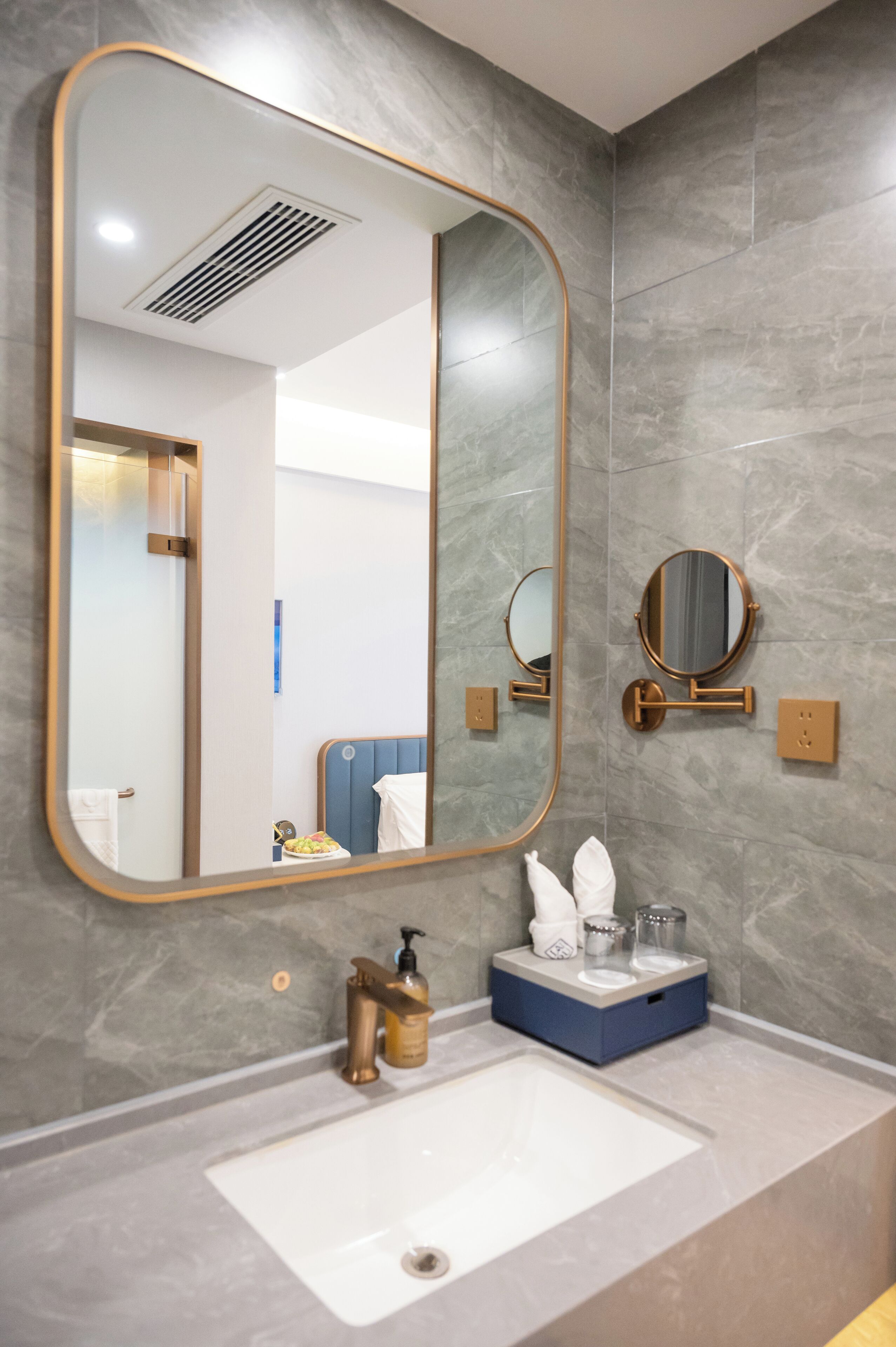 Ein modernes Badezimmer mit einem großen Spiegel, einem Waschbecken und zwei Spiegeln an der Wand.