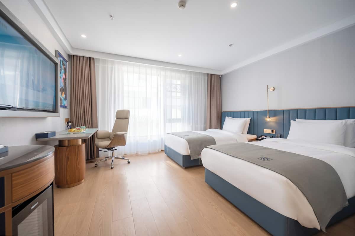 A hotel room with a bed, a desk, a chair, and a TV.