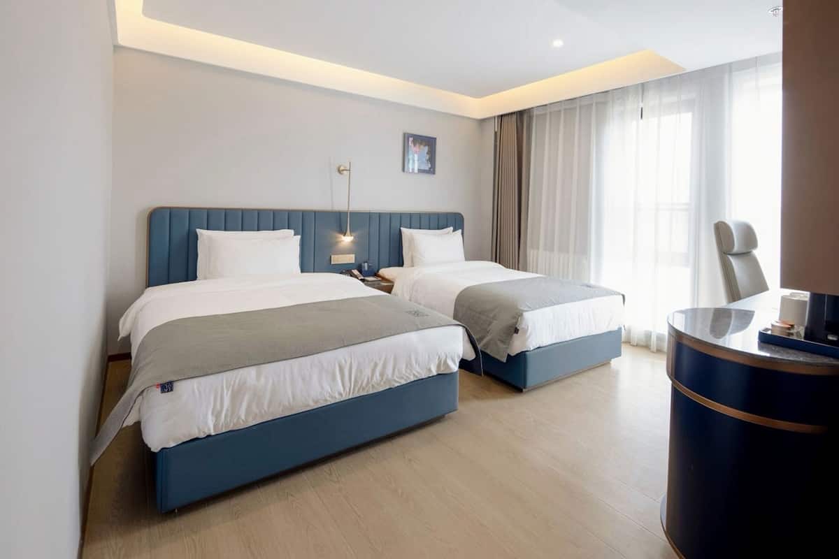A hotel room with two beds, a desk, and a chair.
