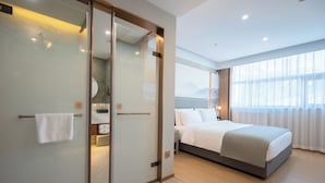 Ett modernt hotellrum med en stor säng, en rymlig klädkammare och utsikt över bergen genom fönstret.