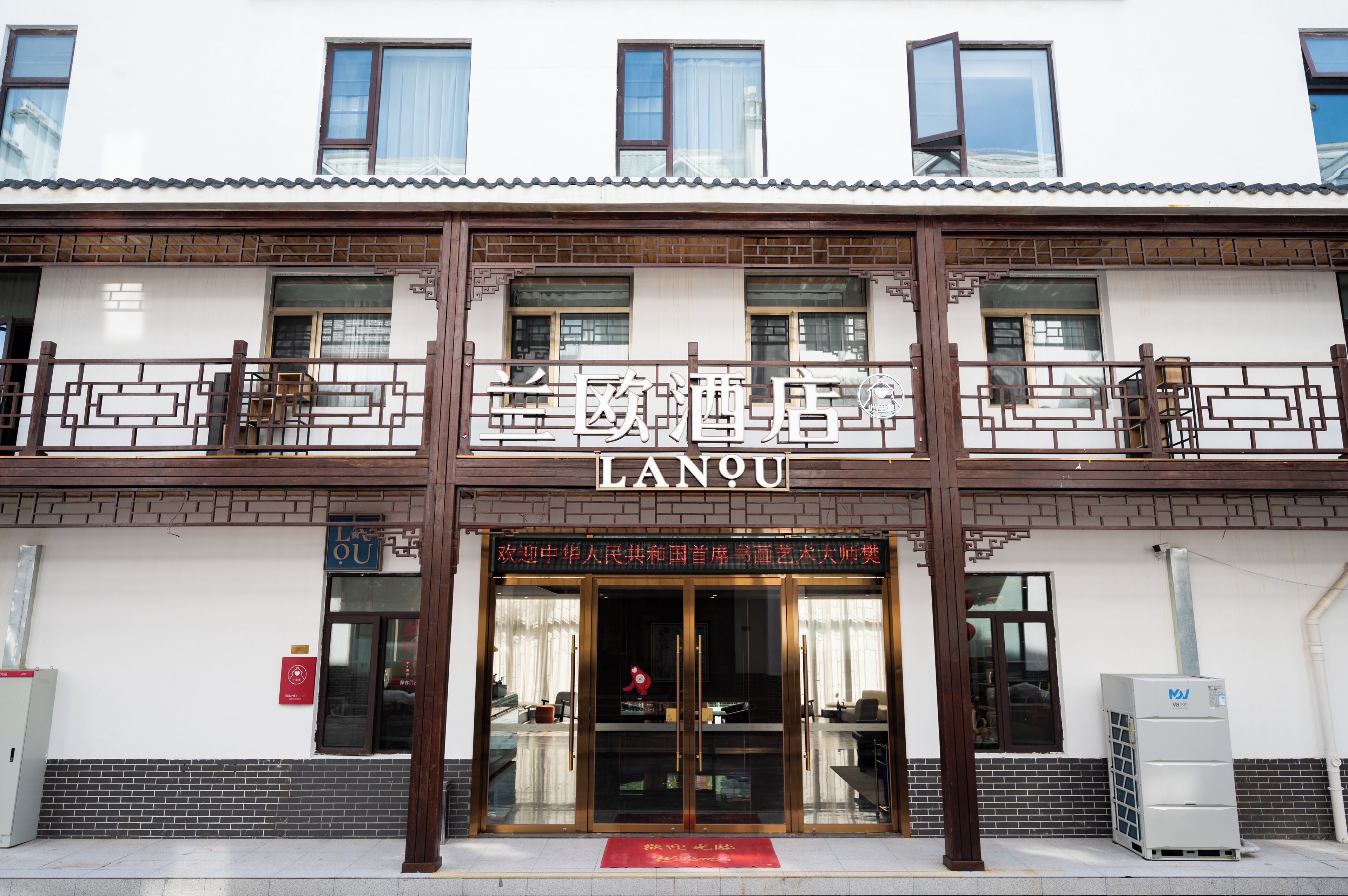 A hotel entrance with a traditional design, featuring a signboard with the name "LANQU".