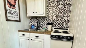 Una cocina pequeña con armarios blancos, una estufa y un salpicadero decorado.