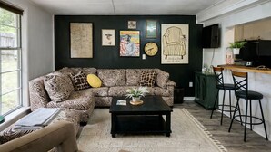 Un salón con un sofá estampado de cebra, una mesa de centro y una zona de bar con taburetes.
