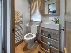 A bathroom with a toilet, a sink, a mirror, and a shelf with decorative items. - 2 bedroom accommodation in Ayr (Ayr)