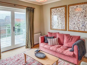 A living room with a red sofa, a coffee table, and two framed floral artworks on the wall.