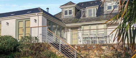 A two-story house with a stone staircase leading to a balcony.