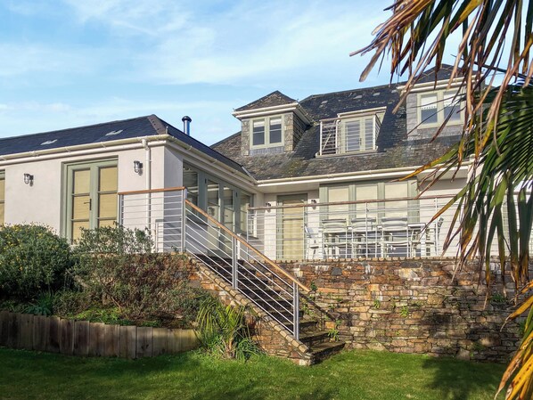 A two-story house with a stone staircase leading to a balcony.