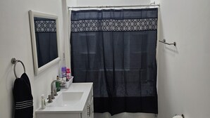 Un bagno piccolo e bianco con lavandino, specchio, WC e tenda da doccia.