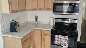 Una cucina con mobili in legno, un forno a microonde, un piano cottura e una macchina da caffè.