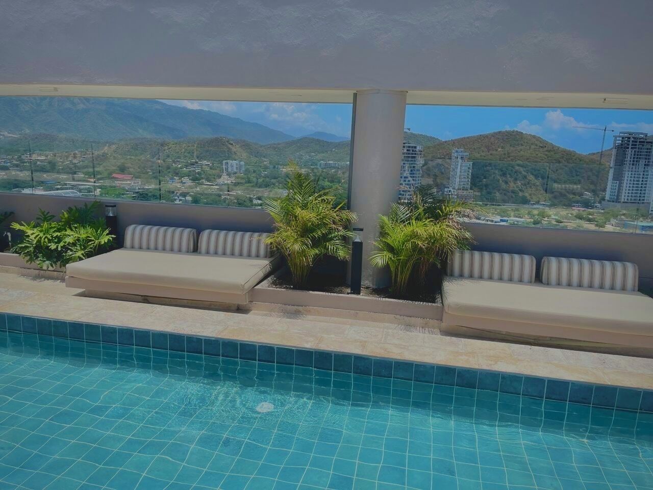 A rooftop pool with a view of mountains and buildings.