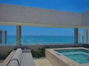 Un balcón con vista al océano, un jacuzzi y una zona de estar.
