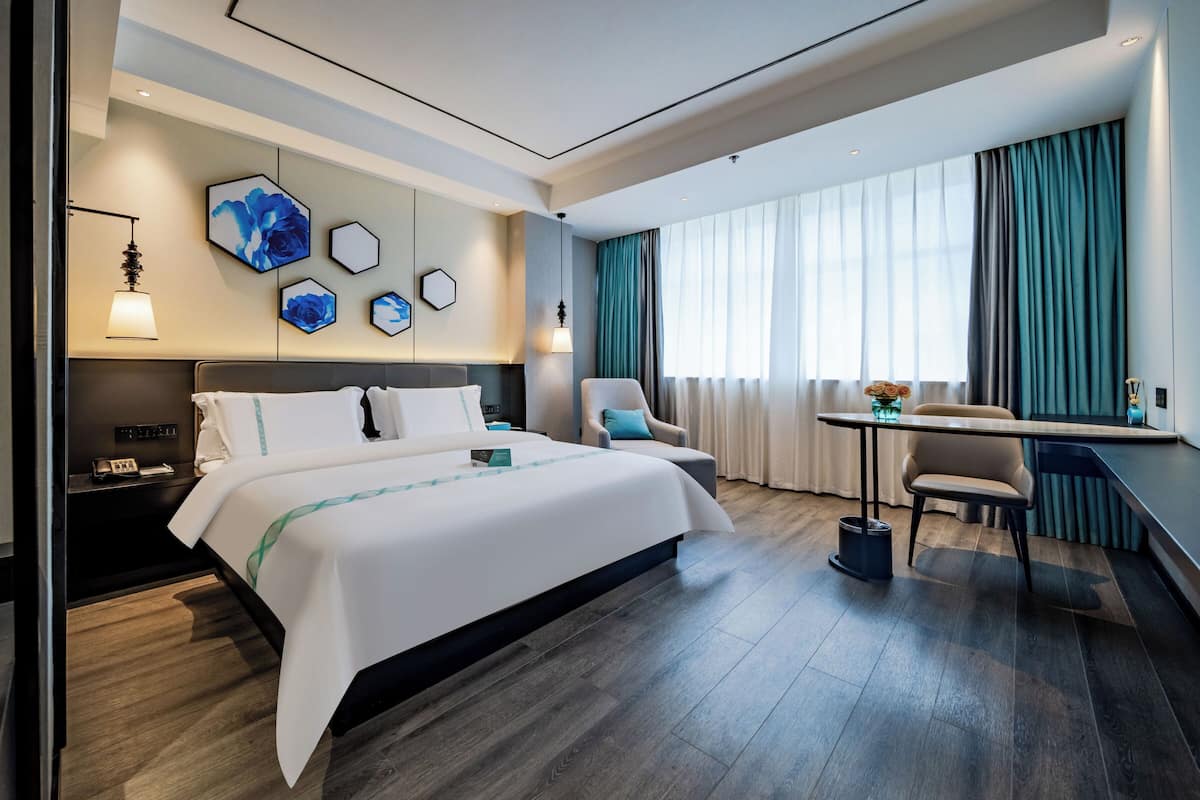 Ein modernes Hotelzimmer mit einem großen Bett, einem Schreibtisch und einem Sessel.
