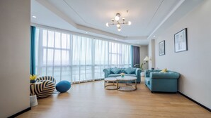 A modern living room with a blue sofa, two round coffee tables, and a chandelier. - XANA Lite Hotel International Guangzhou Baiyun Railway Station Sanyuanli Branch - Free Deliver Service to Canton Fair Complex During Canton Fair Period (Guangzhou)