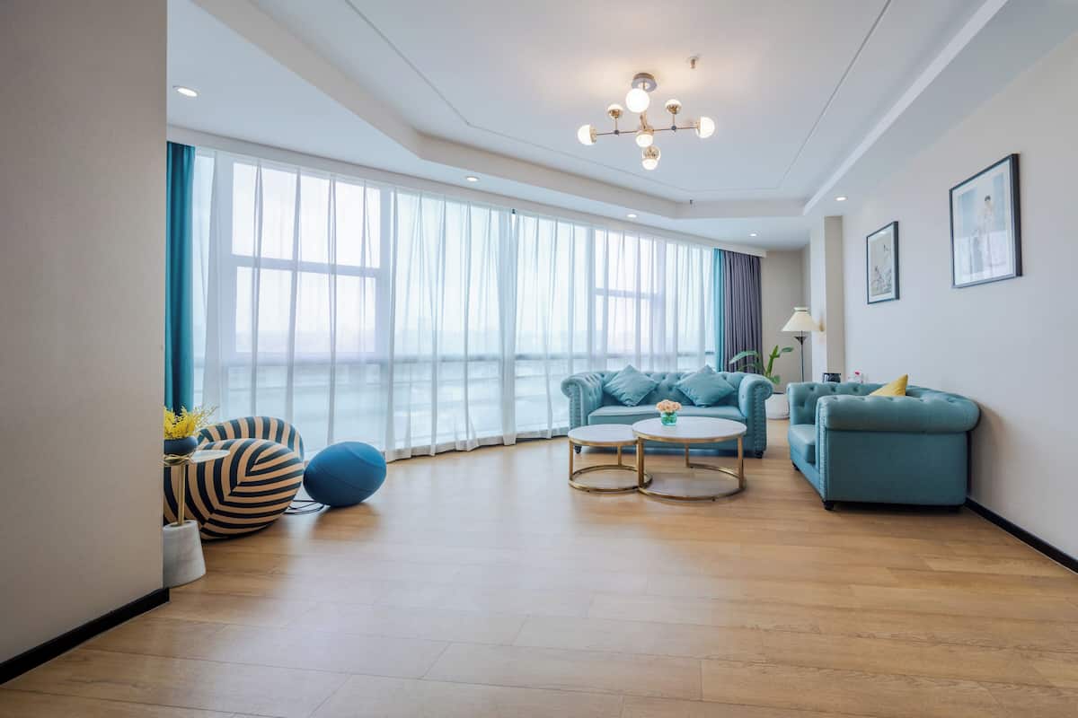 Ein modernes Wohnzimmer mit einem blauen Sofa, zwei runden Couchtischen und einer Chandelier.