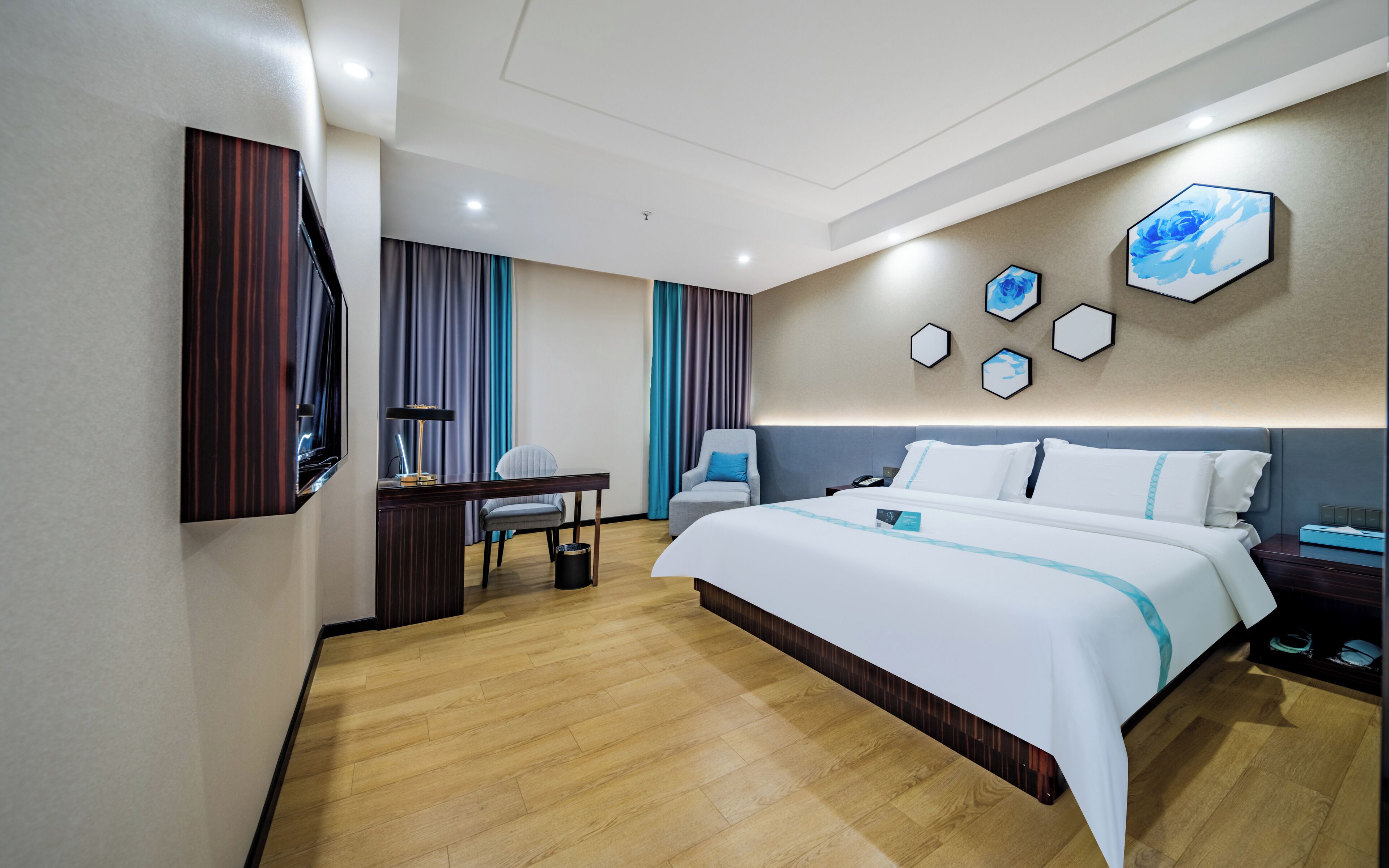 A modern hotel room with a large bed, a desk, a chair, and a television.