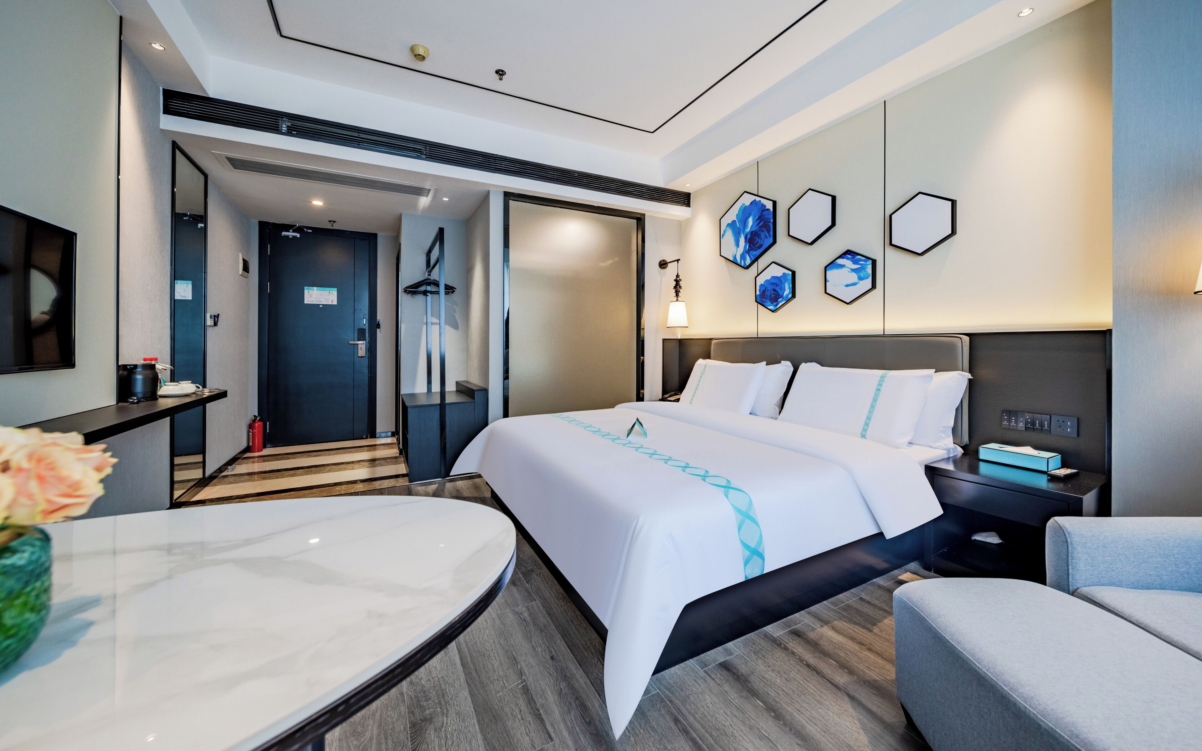Quarto de hotel moderno com uma cama grande, uma mesa e uma área de estar.