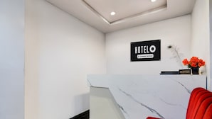A hotel reception area with a marble reception desk, a red chair, and a sign indicating it is a company-serviced hotel. - Hotel O Deendayal Crossway Ranchi (Ranchi)
