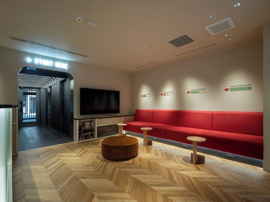 Um lounge moderno com sofá vermelho, piso de madeira e televisão de tela plana.