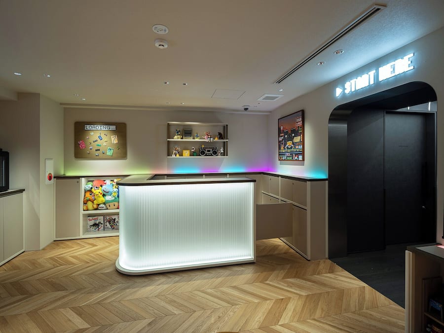 A modern interior with a central counter, wooden flooring, and a neon sign.
