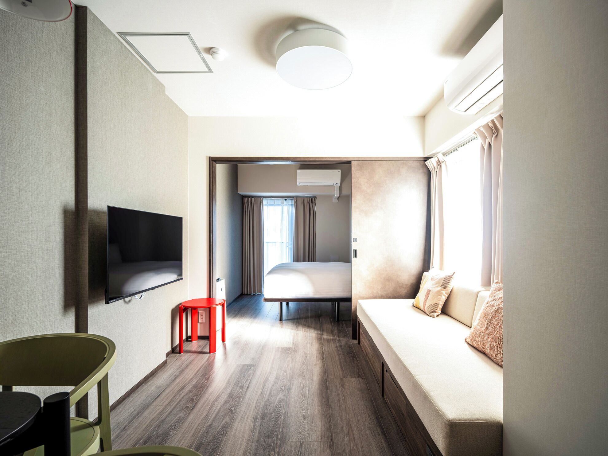 A compact hotel room with a bed, a sofa, a TV, and a small table.