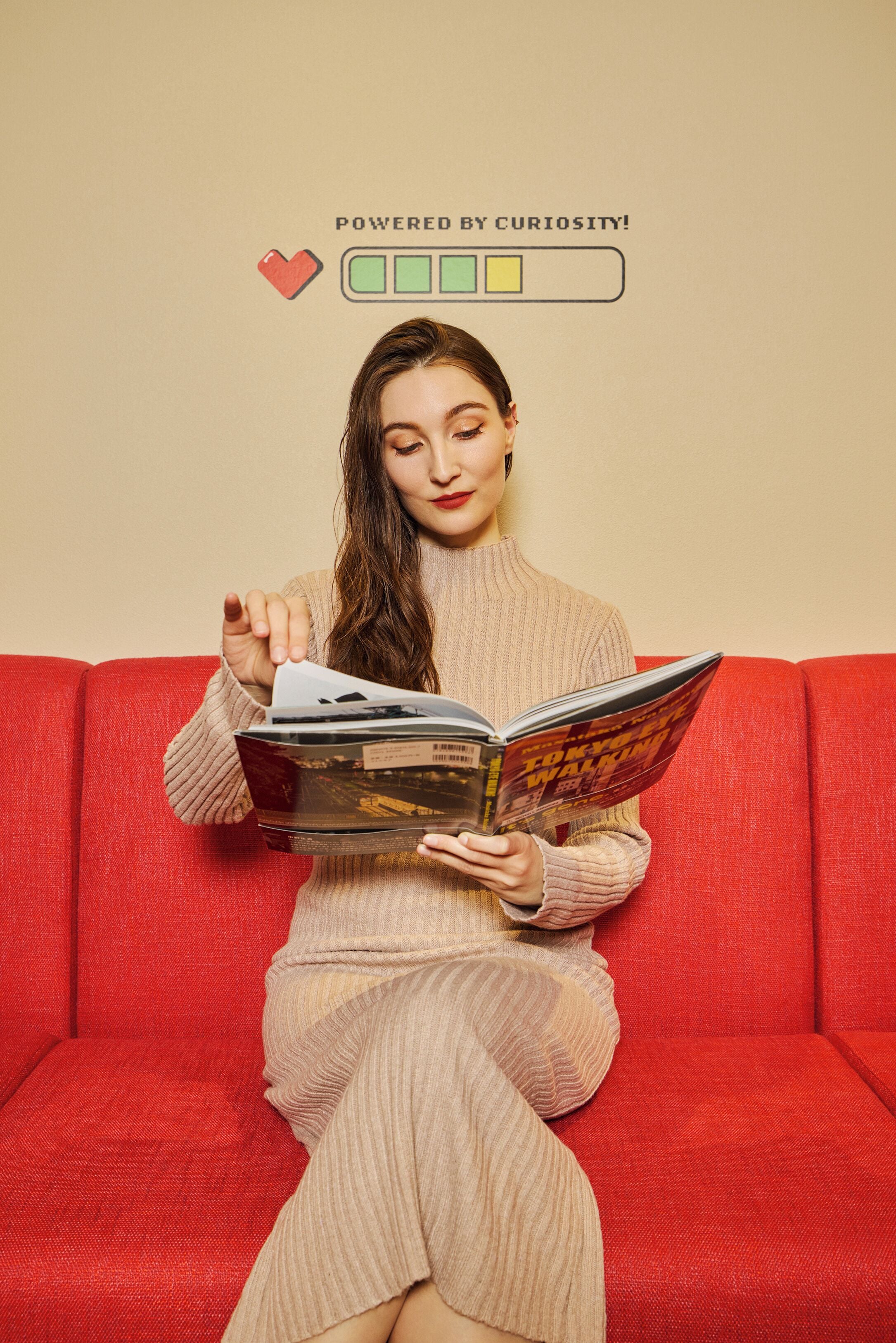 A person sitting on a red couch reading a book.