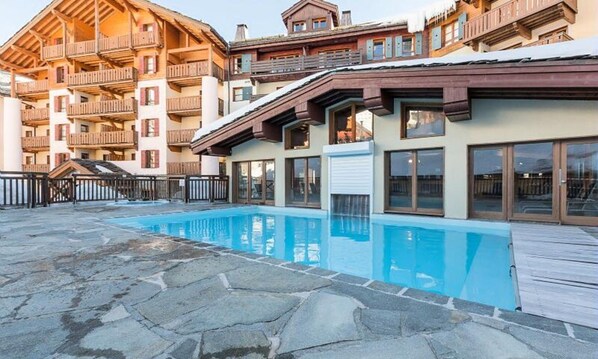 A hotel with a swimming pool, wooden balconies, and a stone deck. - 3 Room Apartment for 6 People Prestige (Bourg-Saint-Maurice)