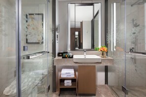 A modern bathroom with a glass shower enclosure, a large mirror, and a vanity with a sink and towel storage. - Hampton by Hilton Beijing Wuzi Xueyuan Road (Tongzhou)
