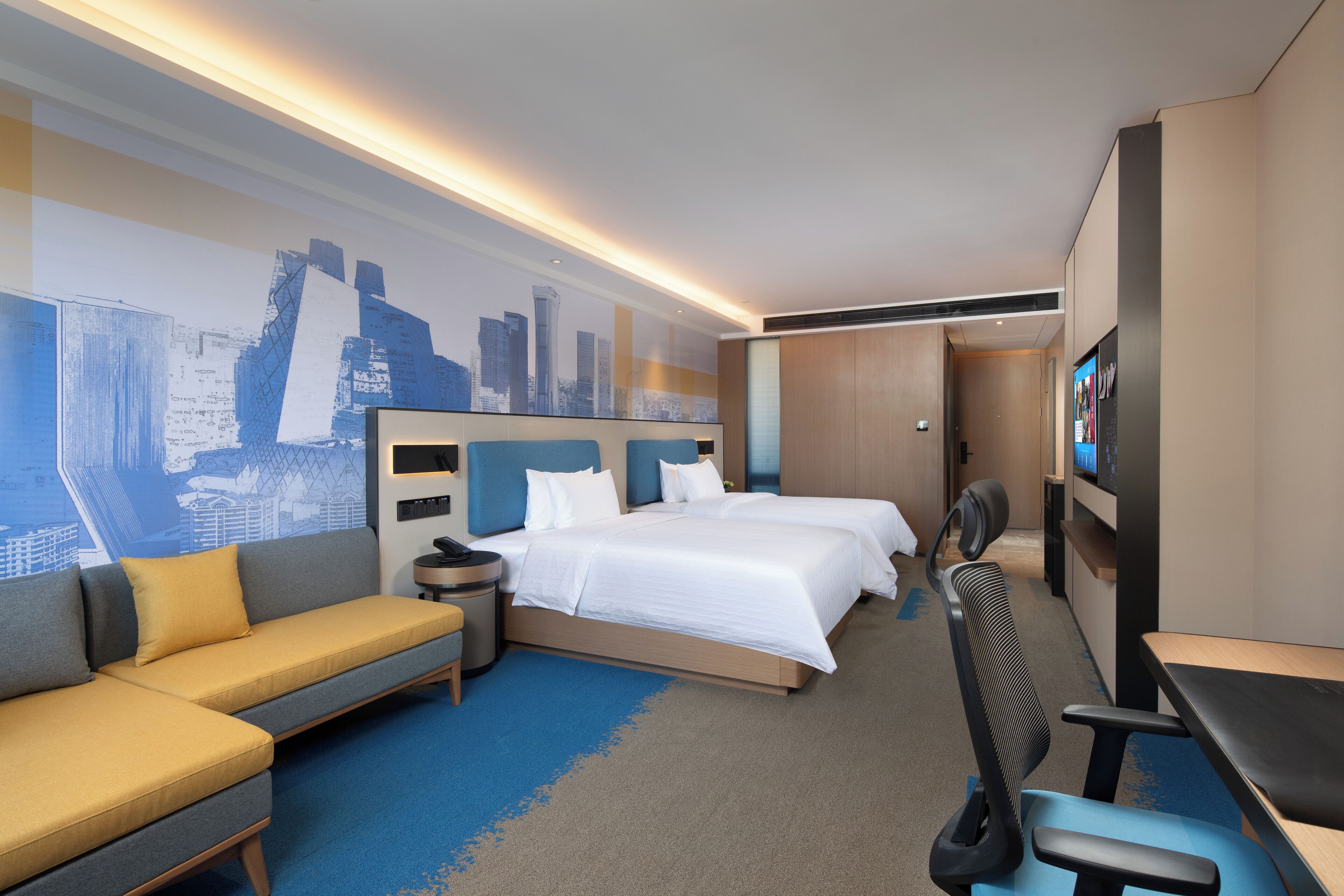Habitación de hotel con dos camas, un sofá, un escritorio, una silla y un televisor.