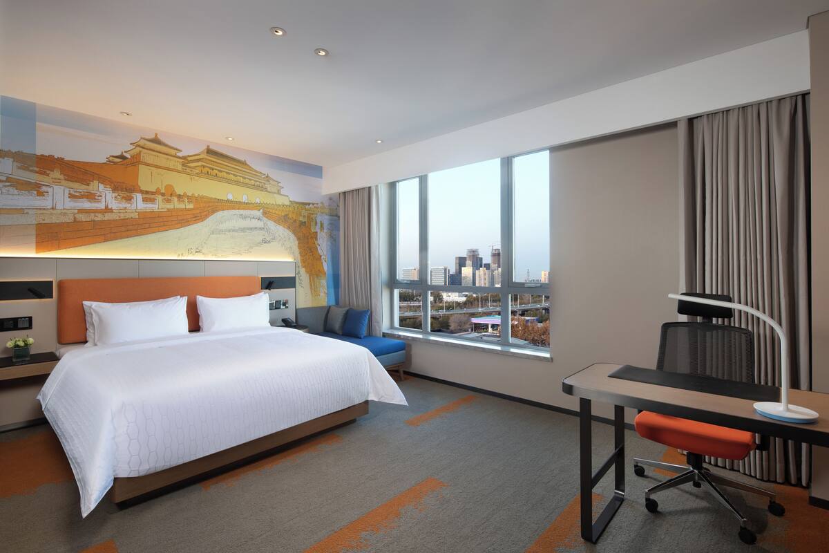 Camera d'albergo moderna con un letto grande, una scrivania e vista sulla città.
