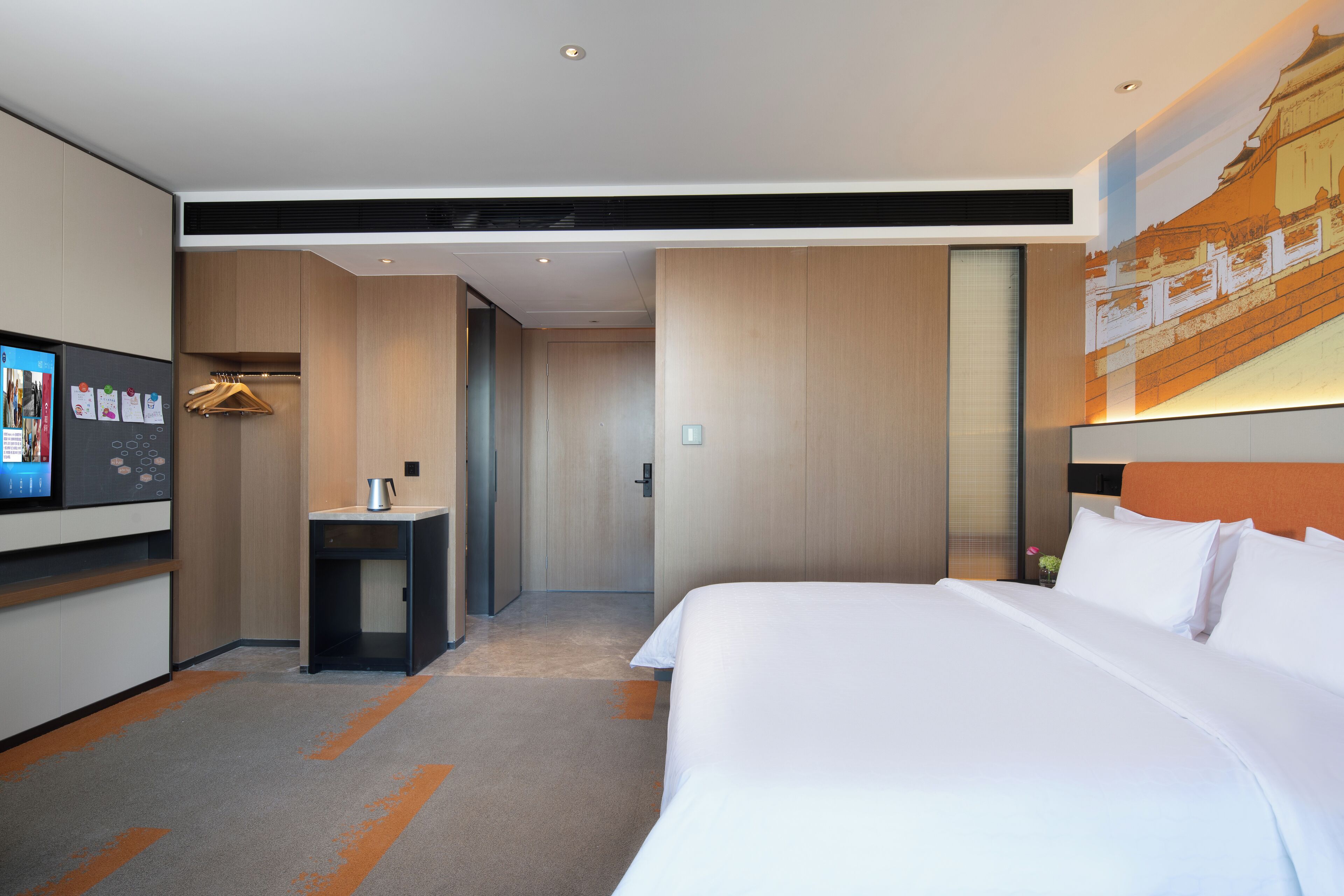 Ein Hotelzimmer mit einem großen Bett, einem Fernseher, einem Schreibtisch und einem Kleiderschrank.