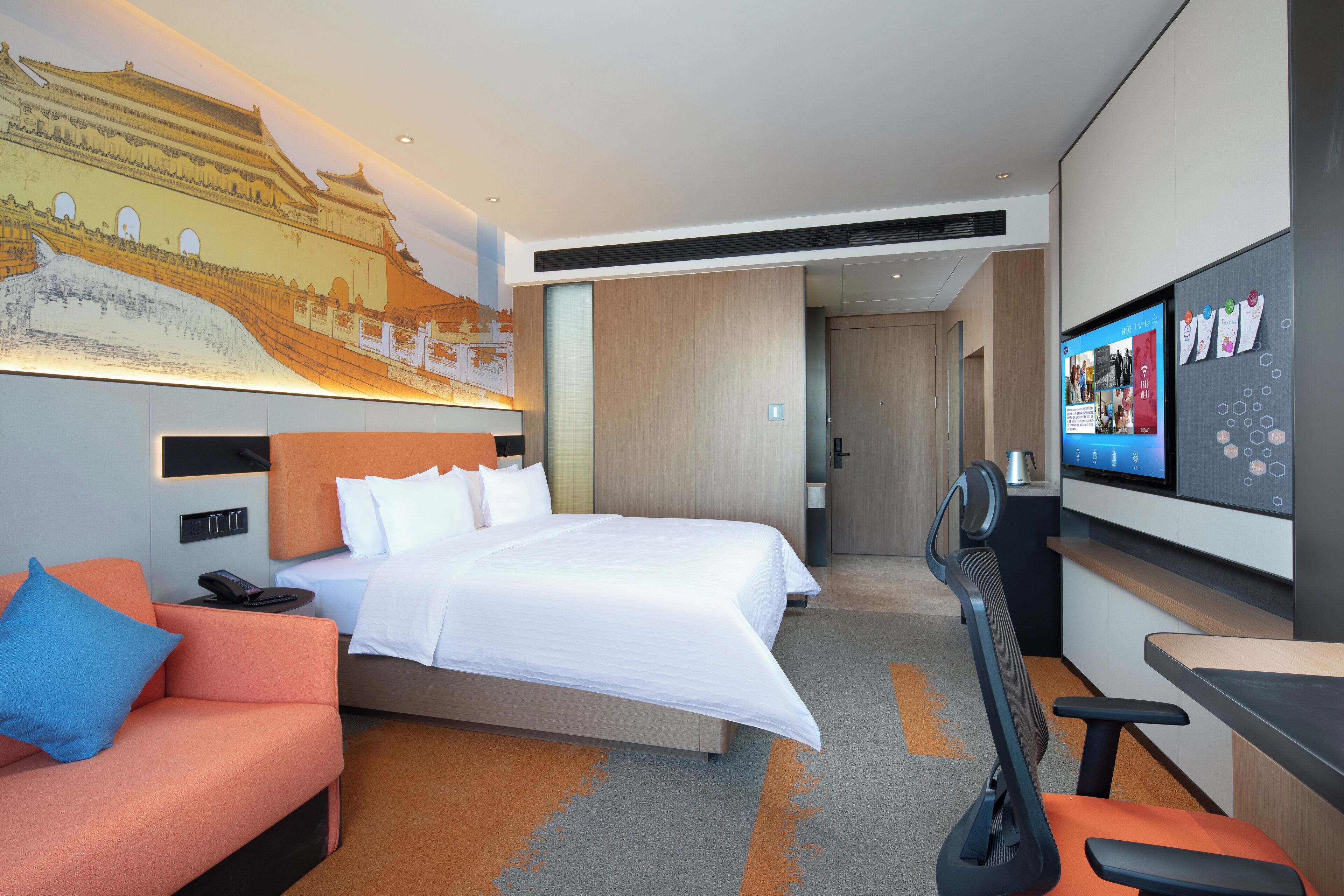 A modern hotel room with a large bed, a sofa, a desk, and a television.