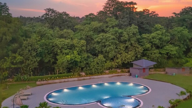 A circular pool with a surrounding deck, a small pavilion, and dense forest in the background. - Corbett Virasat by Vatsam Resorts (Kaladhungi)