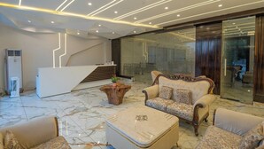 A modern lobby with a reception desk, plush seating, and a staircase. - Corbett Virasat by Vatsam Resorts (Kaladhungi)