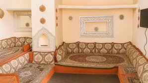A traditional Moroccan-style room with a patterned sofa, a decorative alcove, and wall-mounted decor. - Harari Guest House  (Harar)