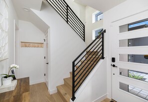 Un escalier avec des rampes noires, des marches en bois et une porte blanche dotée de panneaux de verre.
