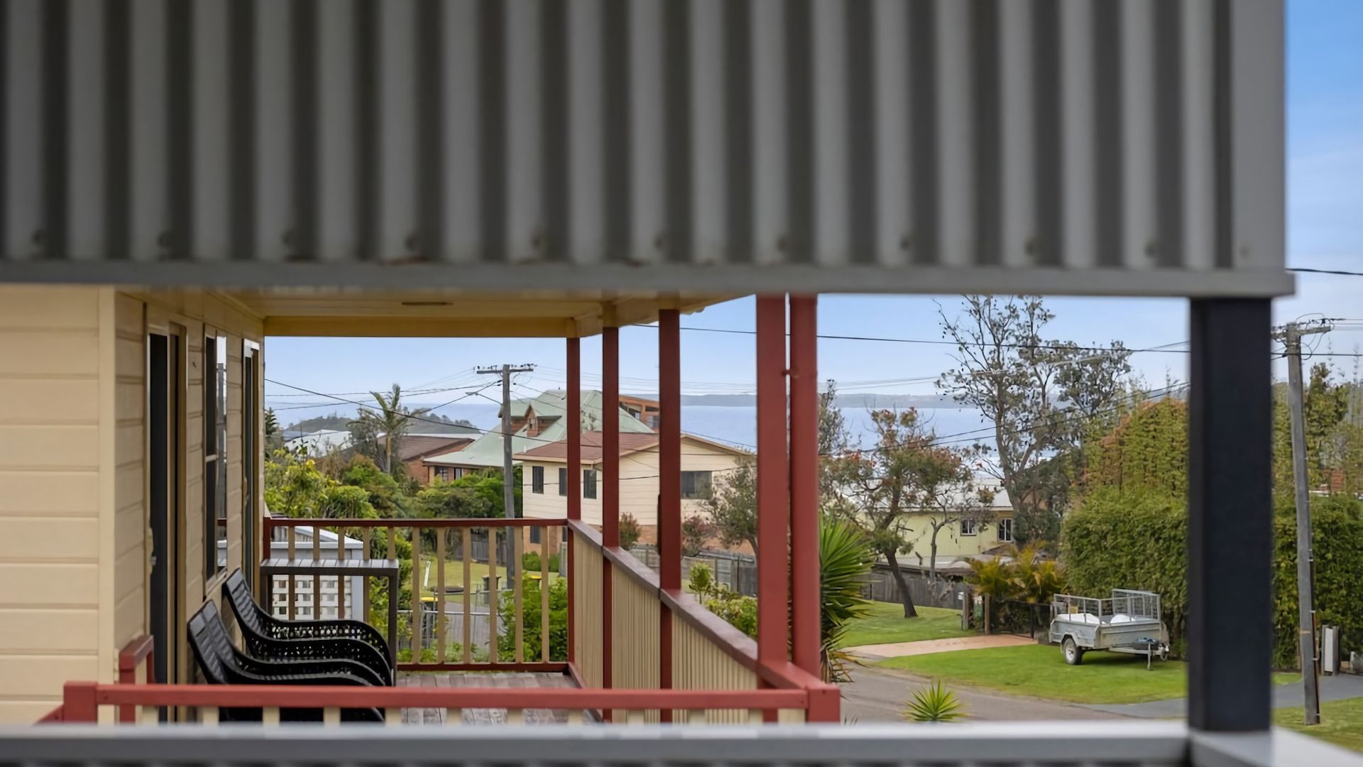 Een woonhuis met een balkon, een auto op de oprit en huizen op de achtergrond.