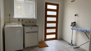 A compact kitchen with a washing machine, a sink, and a door with frosted glass panels. - Manyana Views with expansive views (Manyana)
