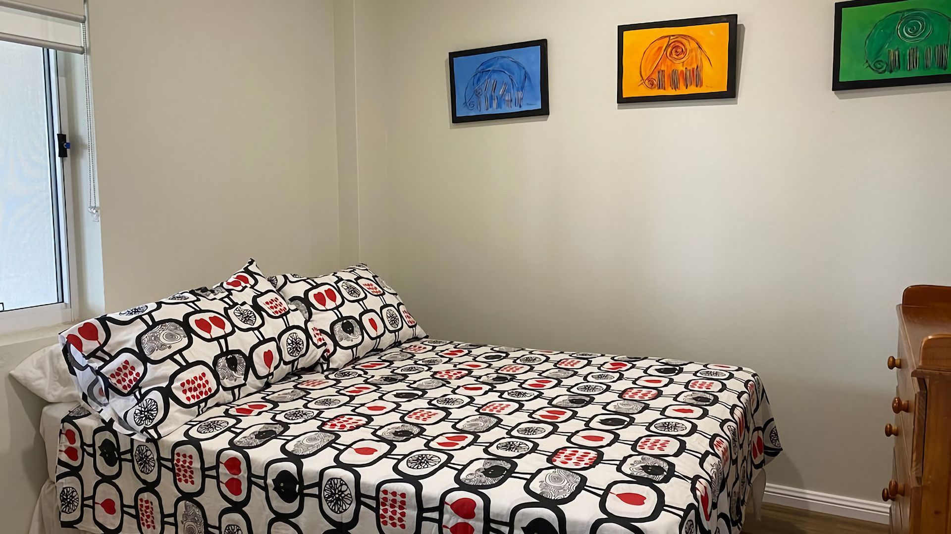 Un dormitorio con cama, cómoda y tres cuadros en la pared.